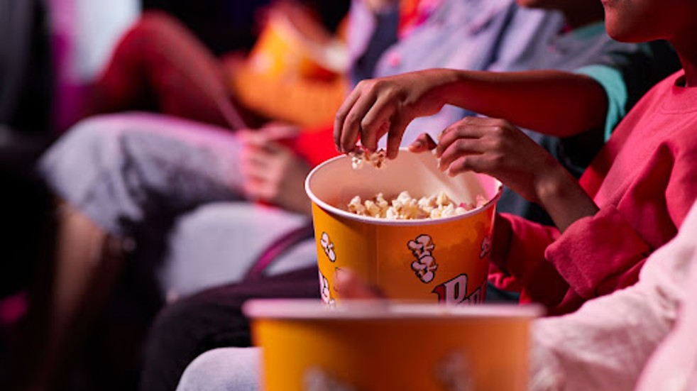 Hands digging into popcorn in cinema